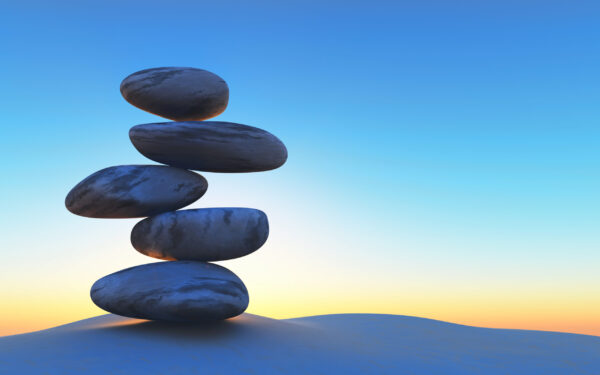 3D render of balancing pebbles on sand against a sunset sky